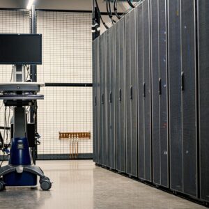 Contemporary computer on support between telecommunication racks and cabinets in modern data center